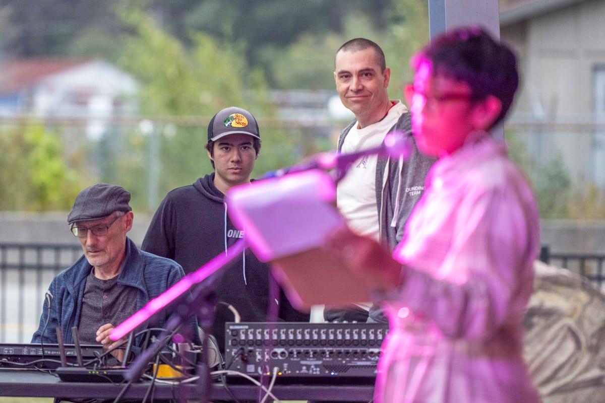 Chris Pettingill standing in the crowd at an outdoor community event in Squamish, watching a performance